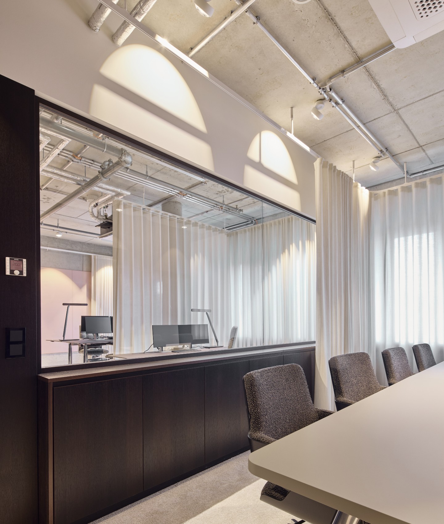 nmp-ventures-glassystemwand Besprechungsraum mit integriertem Meetingbereich, Glassystemwand und maßgefertigten Nussbaum-Einbauten in industrieller Umgebung.